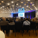 People sitting on chairs with their backs to the camera looking at a presentation screen