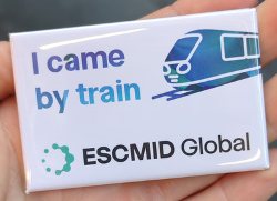 White badge with blue text alongside a picture of a train, indicating the attendee travelled by train to ESCMID Global 2026
